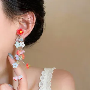 Detailed macro view of vibrant colorful resin flower tassel earrings on an Asian model