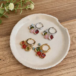 Dettaglio di orecchini a cerchio retrò con nappe di pietre preziose su piatto ceramico