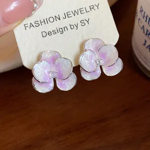Detailed macro view of flower stud earrings with purple oil drip and sparkling zirconia