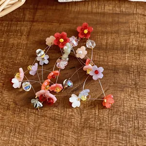 Vibrant resin flower drop earrings with silver needles displayed on a rustic wood