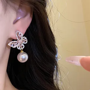 Gros plan d'une boucle d'oreille élégante en forme de papillon avec perle sur l'oreille