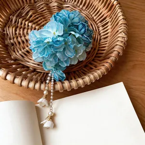 Detailed macro view of a blue fabric flower hair clip with elegant white pearl tassels