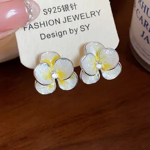 Close-up macro view of delicate enamel and zircon flower earrings with silver needles