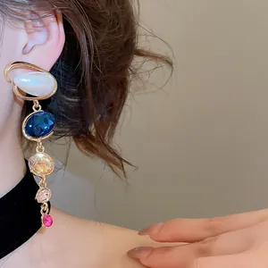 Elegant geometric drop earrings with multi-colored crystals and pearls worn by a model.