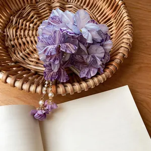 Detailed shot of an elegant purple fabric flower hair clip with pearl tassels