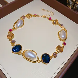 Luxurious close-up of a gold geometric necklace with pearls and colored gemstones.