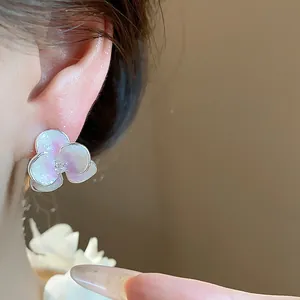 Close-up of elegant enamel flower stud earring with shimmering gradient petals