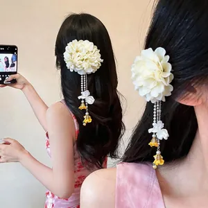 Detailed view of cream floral hair clip with pearl tassels on long dark hair