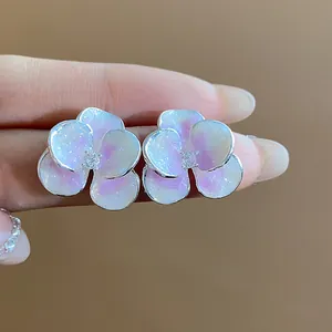 Close-up detail of silver floral earrings with pink gradient petals and zircon centers