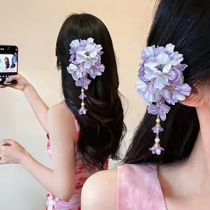 Detailed view of an elegant purple floral fabric hair clip with pearl tassels