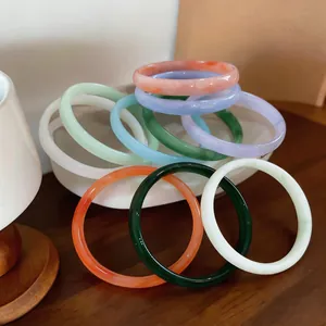Detailed view of colorful chalcedony-style bangles displayed in a decorative white bowl