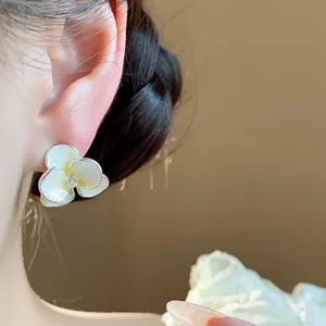 Close-up of elegant flower stud earring with enamel petals and zircon center on ear