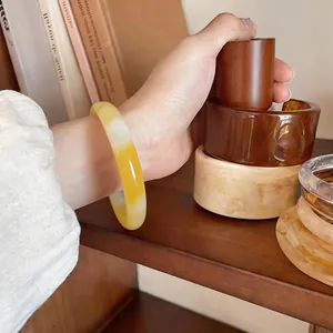 Close-up view of a minimalist yellow marble chalcedony bangle on a woman's wrist.