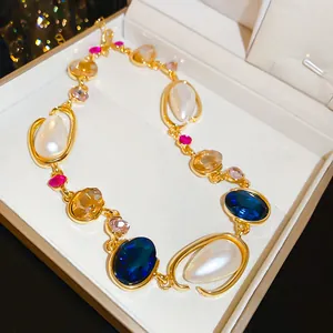 Detailed view of geometric necklace with colorful gemstones and pearls in a gift box