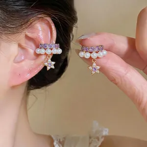 Eleganti orecchini con zirconi viola, perle e stelle mostrati all'orecchio e mano