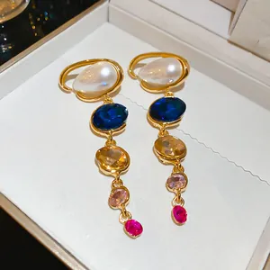 Detailed view of colorful gemstone and pearl drop earrings in a white jewelry box