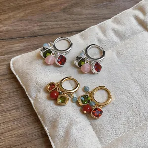 Dettaglio di orecchini a cerchio vintage con nappe di pietre preziose multicolori