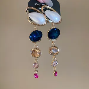 Close-up of elegant long drop earrings with vibrant multi-color gemstones and gold-tone finish