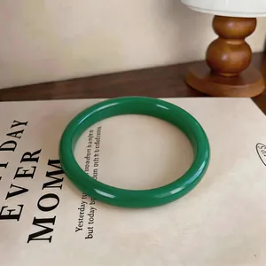 Detailed macro view of a polished green chalcedony bangle placed on a vintage book