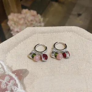 Macro di orecchini retrò con gemme rosse e verdi e perline rosa su espositore