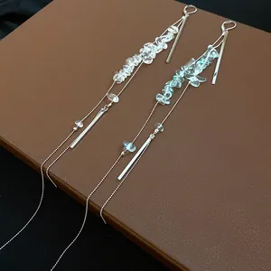 Detailansicht eleganter langer Quastenohrringe mit hellblauen und klaren Steinen.