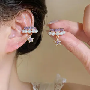 Dettaglio degli orecchini con zirconi viola e perle con pendenti a forma di stella.
