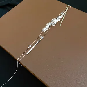 Eleganter langer Quastenohrring mit klaren Steinen und Silberstäben auf braunem Lederhintergrund