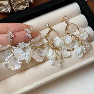 Detail of elegant French style white petal drop earrings with gold finish and zircons