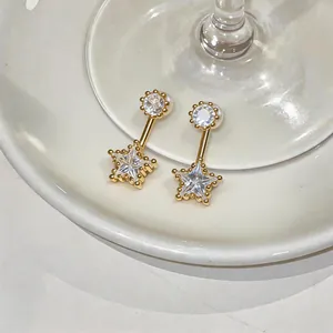 Dettaglio ravvicinato di orecchini a stella dorati con zircone su un piatto di ceramica
