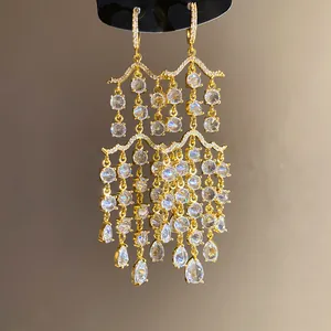 Nahaufnahme eleganter goldener Quastenohrringe mit runden und tropfenförmigen Zirkonia.