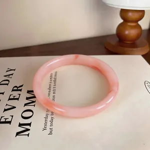 Close-up of elegant pink marble chalcedony bangle on lifestyle background