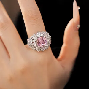 Close-up of a luxurious court style ring with a pink gemstone and zircon halo on a hand