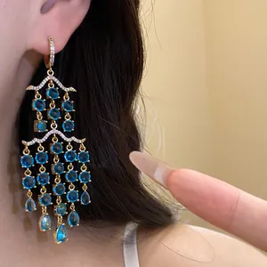 Makroaufnahme eleganter goldener Kronleuchter-Ohrringe mit funkelnden blauen Zirkonia