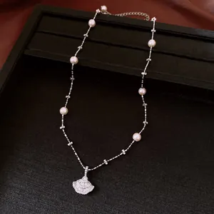 Dettaglio di un elegante ciondolo in zircone a forma di ventaglio e collana di perle