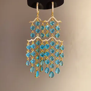 Detailansicht der vergoldeten Kronleuchter-Ohrringe mit blauen runden und birnenförmigen Zirkonia.