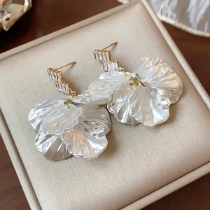 Close-up macro view of French style gold earrings with pearlized petal shell and zirconia