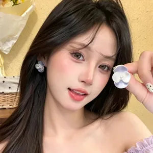 Detailaufnahme eines asiatischen Models mit eleganten lila Blumenohrringen mit Perlenbesatz