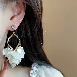 Close-up detail of French style zircon petal shell tassel drop earrings worn by an Asian model