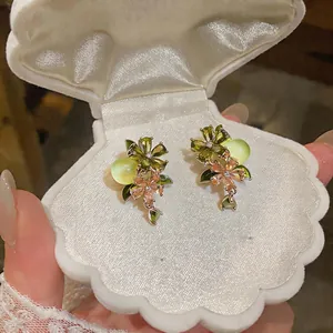 Detailed macro view of elegant floral zircon earrings featuring green and pink stones