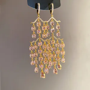 Detaillierte Nahaufnahme von rosa Zirkonia-Quastenohrringen mit Wassertropfen.