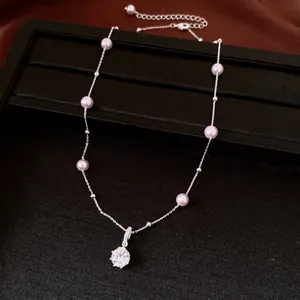 Primo piano di una collana d'argento con perle e un ciondolo tondo in zirconia cubica