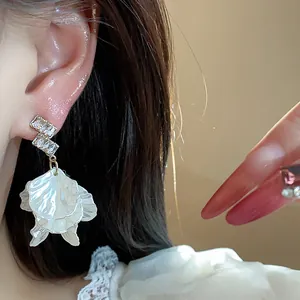 Close-up detail of elegant French style zircon shell petal drop earrings worn on ear
