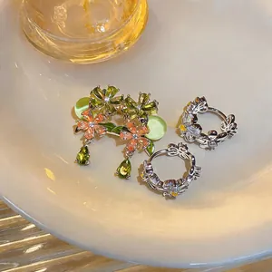 Detailed view of floral zircon earrings and green teardrop jewelry on a ceramic plate