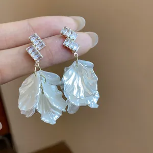 Elegant silver needle earrings with zircon studs and white shell petal tassels, detail view.