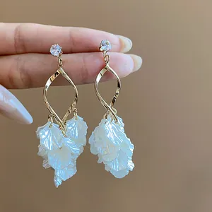 Detailed view of elegant shell petal tassel earrings with gold-tone twist and zircon studs