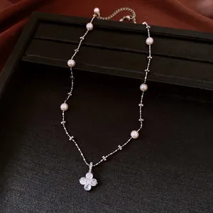 Primo piano di un'elegante collana di perle con ciondolo a fiore in zircone a 4 petali.