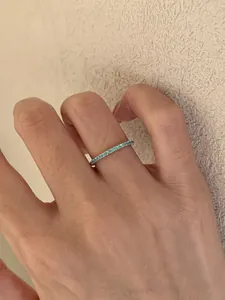 Detailansicht eines zierlichen Silberrings mit funkelnden mintgrünen Steinen am Finger