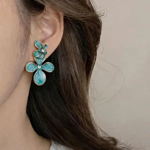 Boucles d'oreilles pendantes fleurs en émail bleu avec strass sur un mannequin