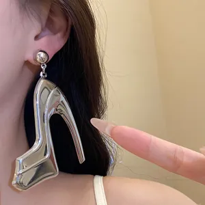 Detailed close-up showing a large metallic silver high-heeled shoe pendant earring worn