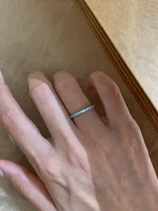 Detaillierte Nahaufnahme eines minimalistischen mintgrünen Rings am Finger einer Dame